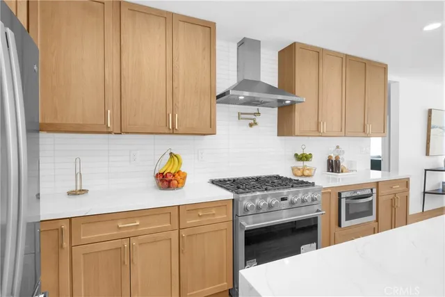 a kitchen with stainless steel appliances granite countertop a stove a sink dishwasher and white cabinets with wooden floor