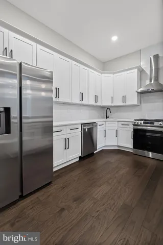 a kitchen with stainless steel appliances granite countertop a refrigerator a stove a sink and white cabinets