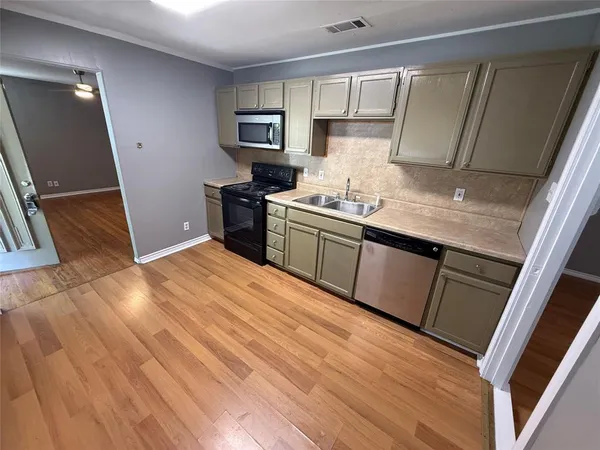 a kitchen with a sink a stove top oven and cabinetry