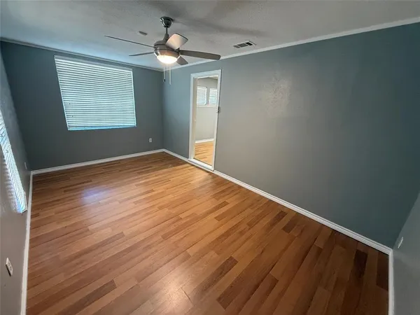 a view of an empty room with window and wooden floor