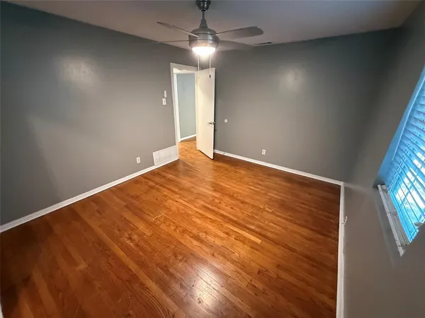 an empty room with chandelier fan and windows