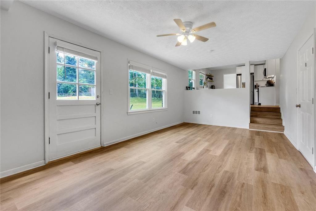 5800 Cedar Lane Southwest Mableton, GA 30126 - Photo 12 of 41 an empty room with wooden floor chandelier fan and windows