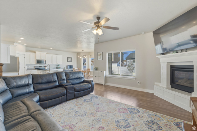 836 South 250 West Vernal, UT 84078 - Photo 19 of 56 Living room featuring a ceiling fan, dark wood-type flooring, a glass covered fireplace, and a chandelier