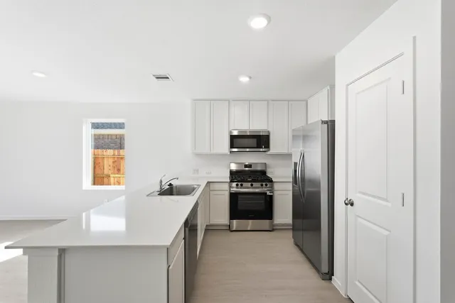 a kitchen with cabinets stainless steel appliances and a window
