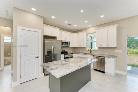 a kitchen with stainless steel appliances granite countertop a sink refrigerator and cabinets