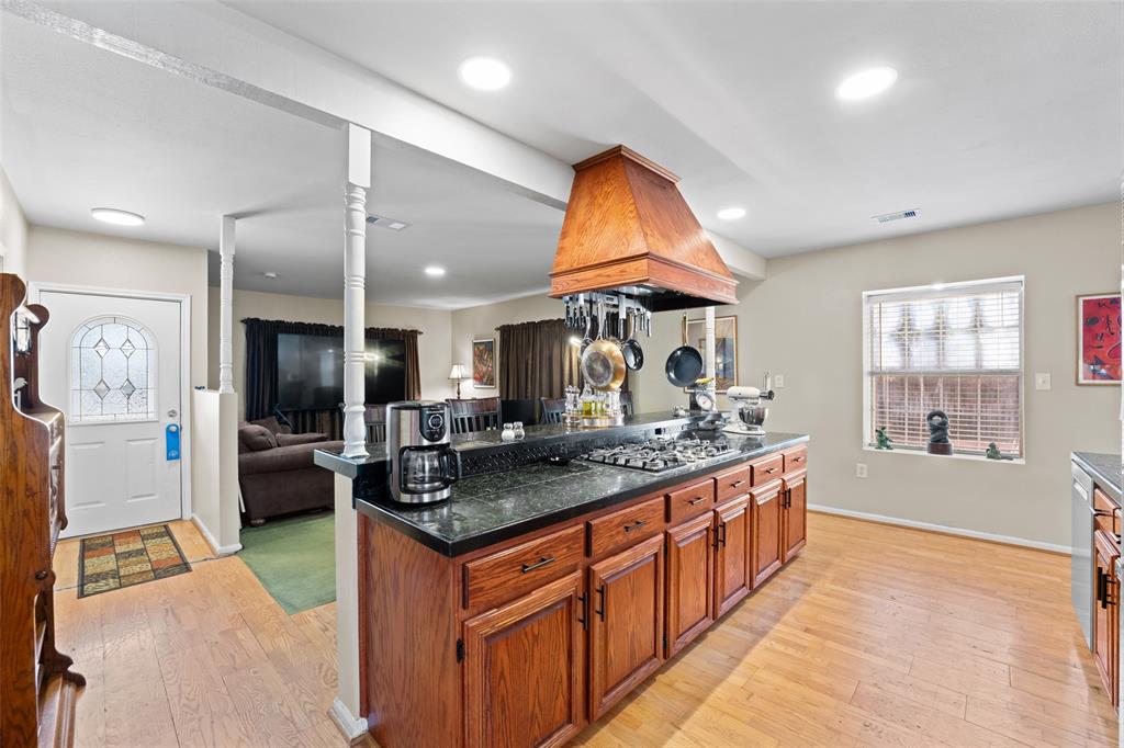 805 East Shady Grove Road Irving, TX 75060 - Photo 36 of 36 Kitchen with light wood-style floors, wood finish cabinetry, a kitchen island, open floor plan, and a kitchen breakfast bar