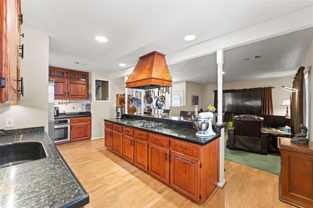 805 East Shady Grove Road Irving, TX 75060 - Photo 35 of 36 Kitchen with wood finish cabinetry, stainless steel appliances, light wood finished floors, glass insert cabinets, and open floor plan