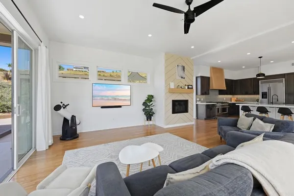 a kitchen with stainless steel appliances granite countertop a stove a refrigerator a microwave a dining table and chairs with wooden floor