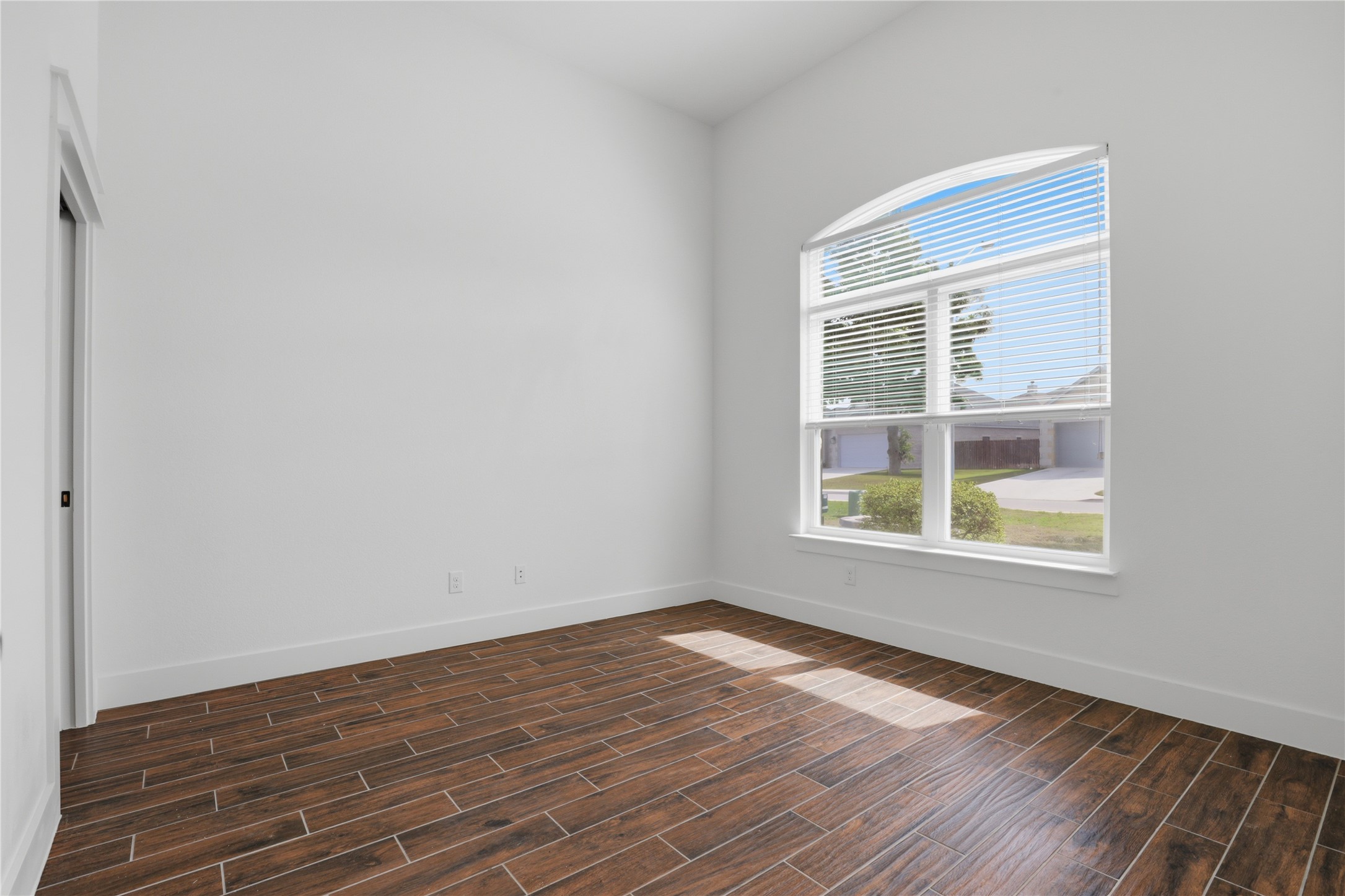133 Greg Lane Jarrell, TX 76537 - Photo 18 of 24 Spacious room featuring vaulted ceilings, wood-finish flooring, white baseboards, and a large arched window with blinds