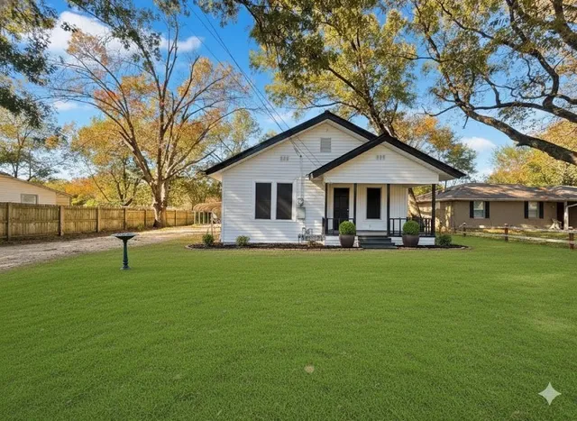 a front view of a house with a garden and trees