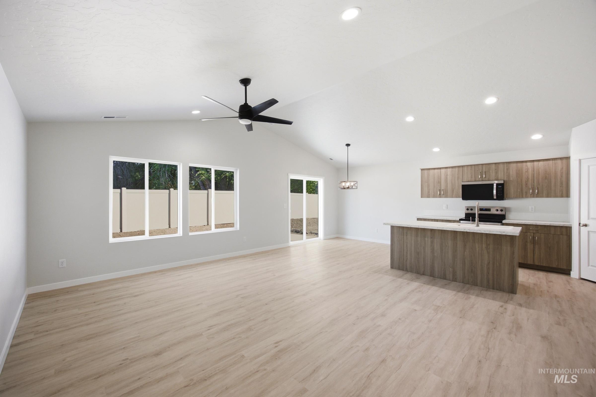 13298 Bank Street Caldwell, ID 83607 - Photo 7 of 23 Vaulted ceilings with recessed lighting, wood-finish flooring, a kitchen island with stone countertops, and modern wood-look cabinetry