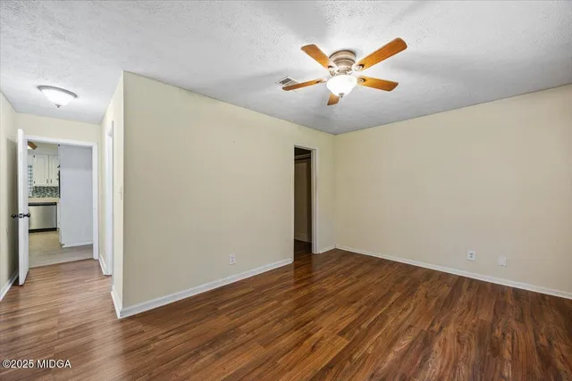 an empty room with wooden floor and a ceiling fan