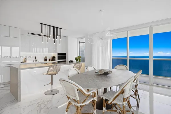 a living room with furniture a rug and white kitchen view