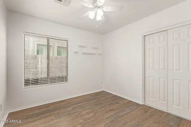 an empty room with wooden floor closet and windows