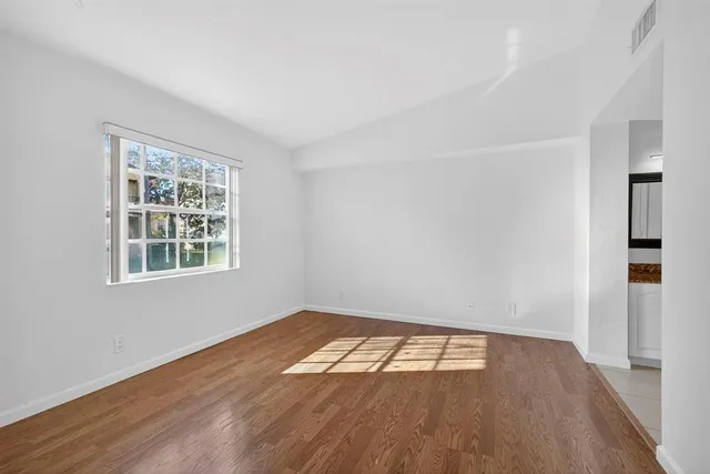 an empty room with wooden floor and windows