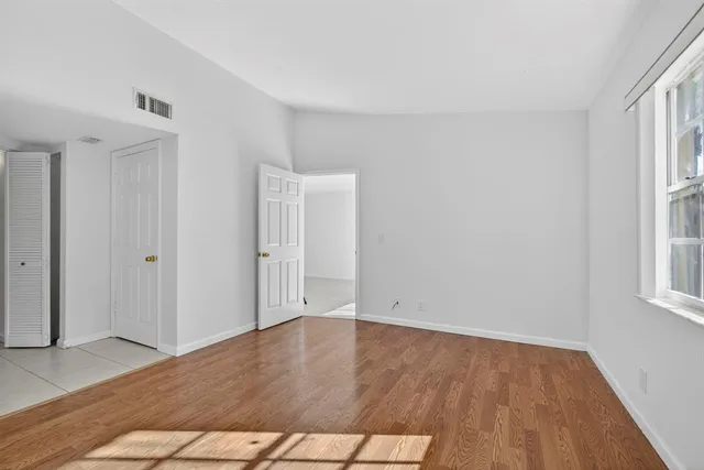 an empty room with wooden floor and windows
