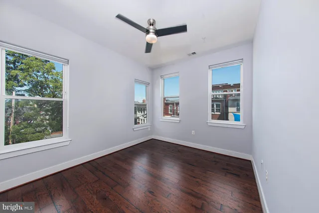 a view of empty room with wooden floor and fan