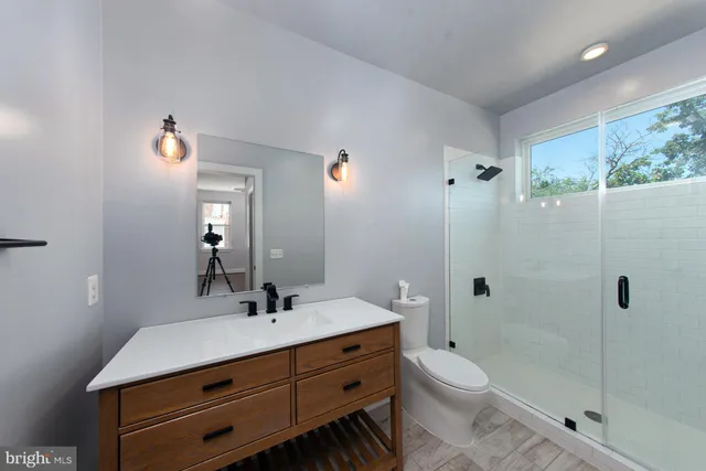 a bathroom with a shower sink vanity mirror and toilet