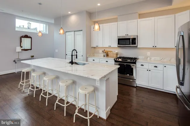 a kitchen with stainless steel appliances granite countertop a stove a sink dishwasher and a refrigerator with wooden floor