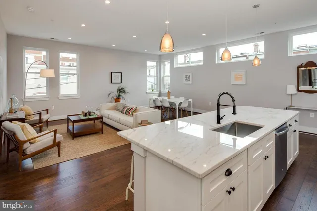 a kitchen with stainless steel appliances granite countertop a sink dishwasher a couches with wooden floor