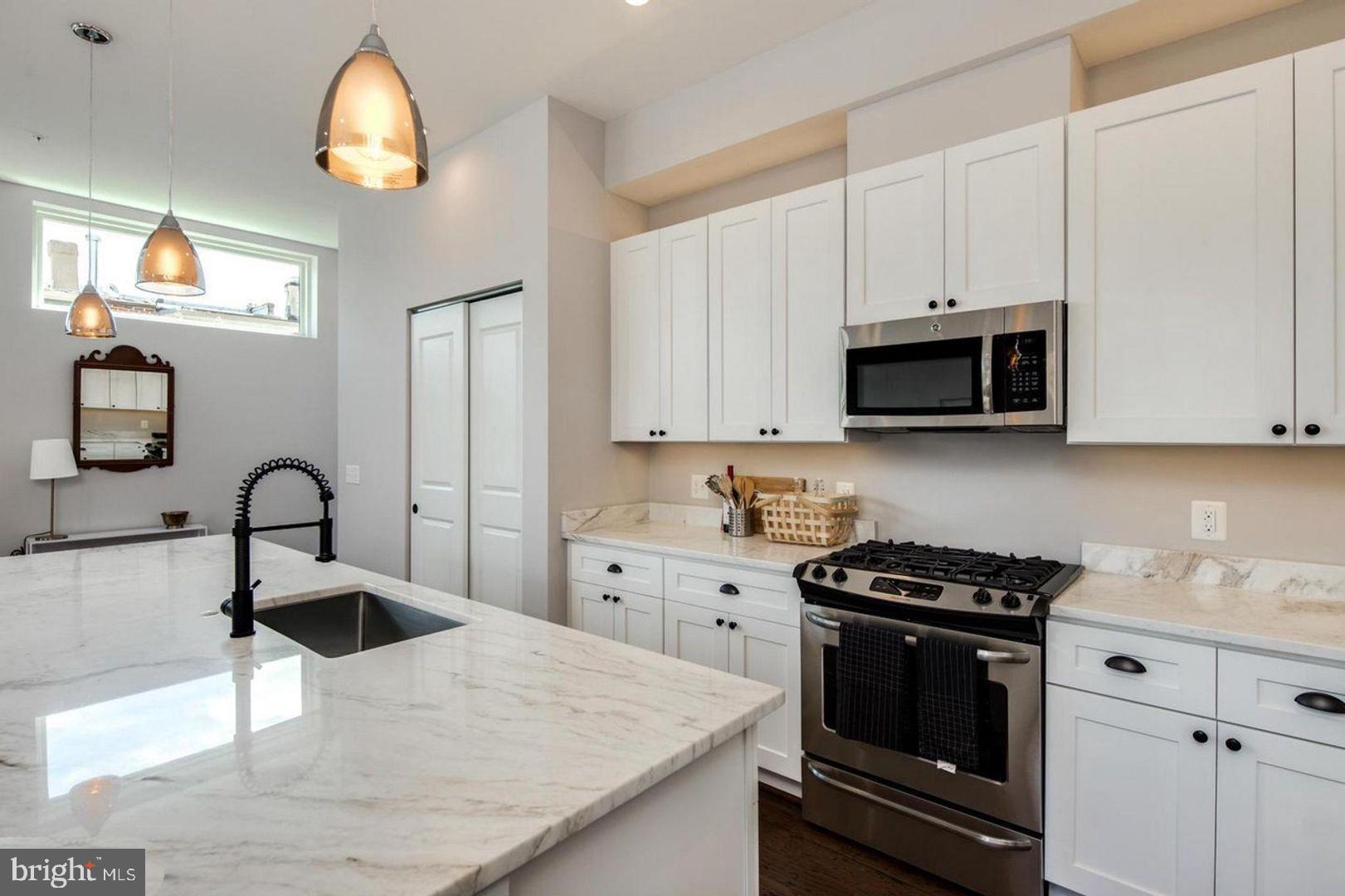 3542 Warder Street Northwest, Unit 204 Washington, DC 20010 - Photo 10 of 29 a kitchen with kitchen island granite countertop a sink a stove and cabinets