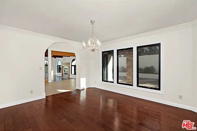 a view of a big room with wooden floor chandeliers and kitchen view
