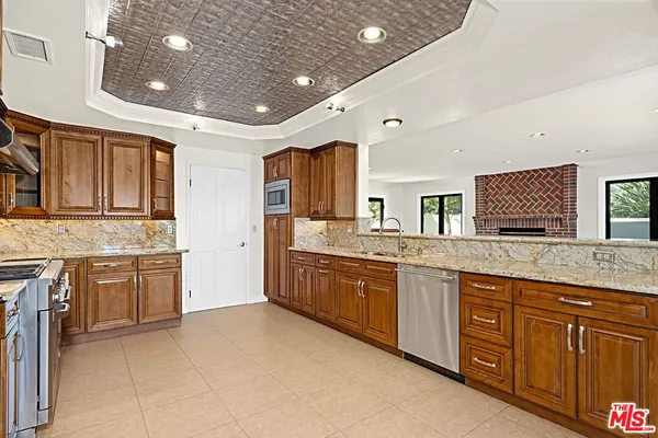 a large kitchen with granite countertop a sink dishwasher stove and cabinets