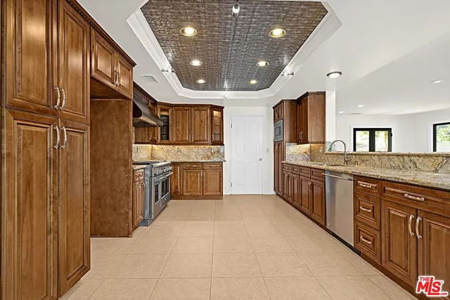 a large kitchen with stainless steel appliances a sink counter space and wooden floor