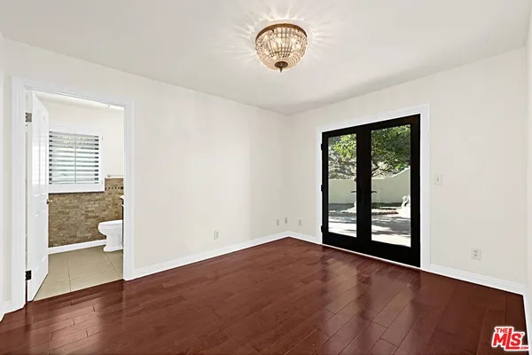 an empty room with wooden floor cabinet and windows