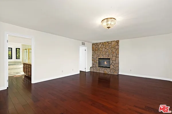 an empty room with wooden floor fireplace and windows