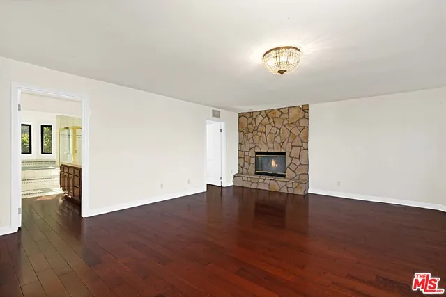 an empty room with wooden floor fireplace and windows