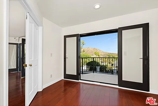 a view of a room with a large window and wooden floor