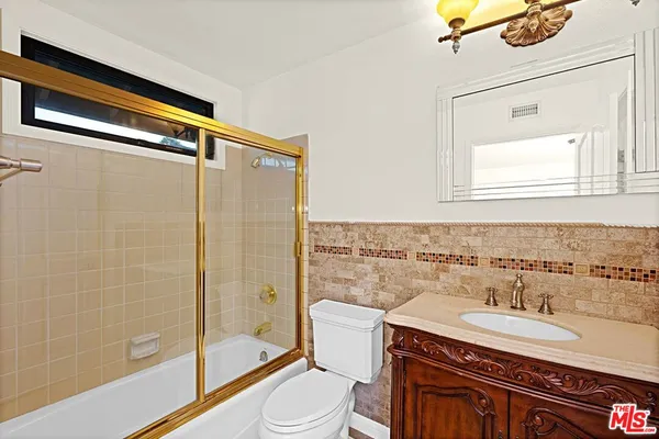 a bathroom with a granite countertop sink toilet a mirror and shower