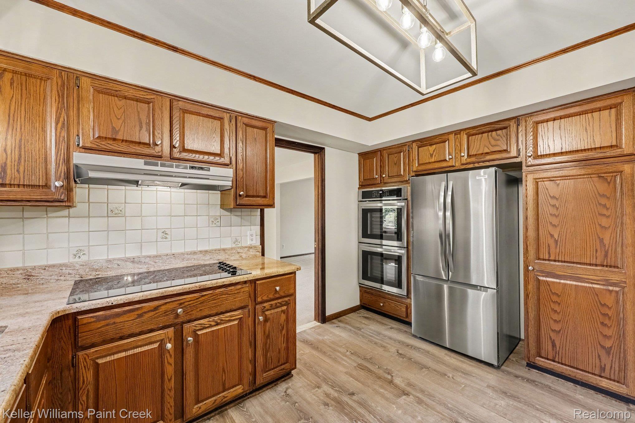 2717 Powderhorn Ridge Road Rochester, MI 48309 - Photo 5 of 48 Wood-finish flooring, wood cabinetry, stainless steel double wall ovens, stainless steel refrigerator, and a tile backsplash