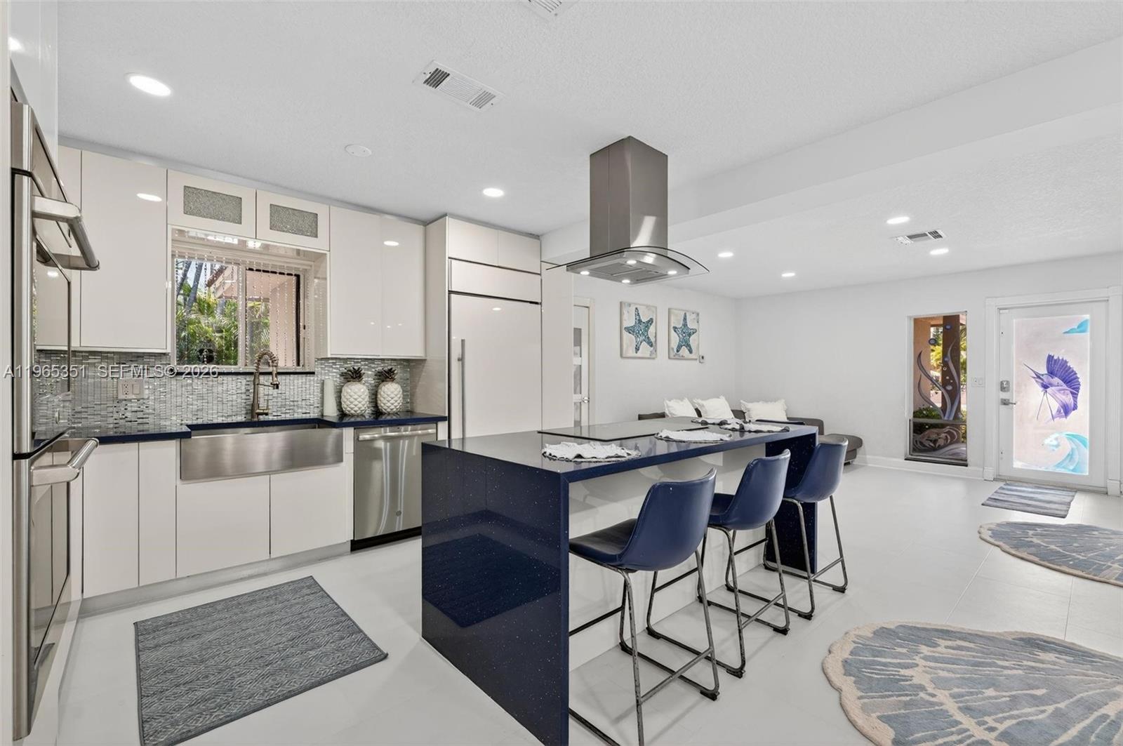 317 South Riverside Drive Pompano Beach, FL 33062 - Photo 8 of 25 a kitchen with stainless steel appliances kitchen island granite countertop a table chairs sink and cabinets