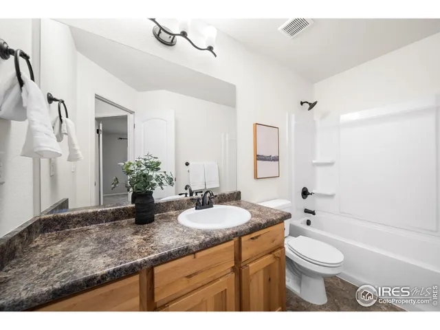 a bathroom with a granite countertop sink a toilet a mirror and bathtub
