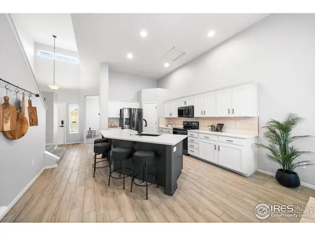 a open kitchen with kitchen island a refrigerator a stove a sink dishwasher a dining table and chairs with wooden floor