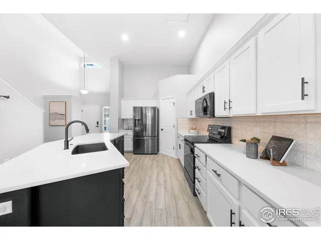 a kitchen with stainless steel appliances a sink dishwasher a stove a refrigerator and white cabinets with wooden floor