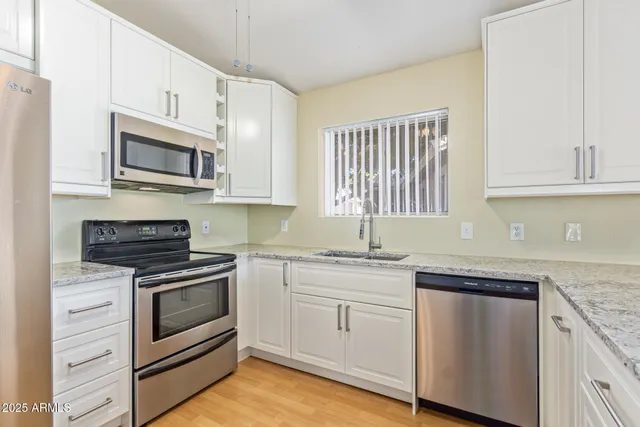 a kitchen with granite countertop cabinets stainless steel appliances and a sink