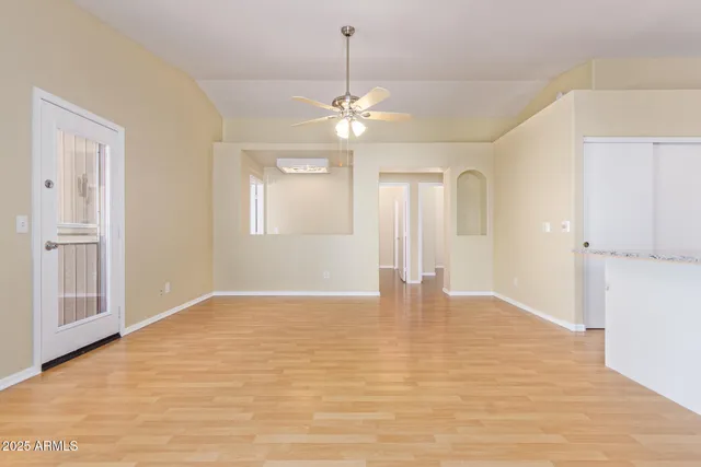 a view of an empty room with chandelier fan and wooden floor