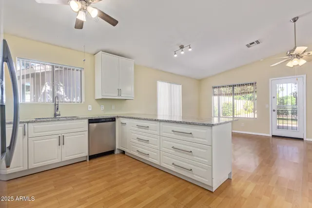 a kitchen with granite countertop a stove a sink and white cabinets with wooden floor