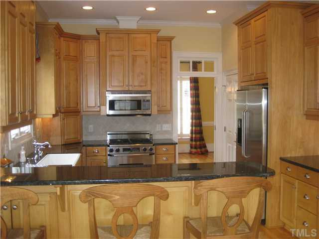6104 Wilkinsburg Road Raleigh, NC 27612 - Photo 4 of 18 a kitchen with stainless steel appliances granite countertop a refrigerator a stove and a sink with wooden floor