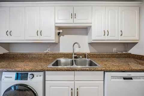a kitchen with granite countertop white cabinets and sink