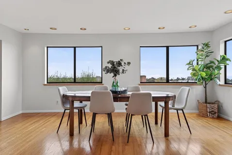 a dining room with furniture potted plants and wooden floor