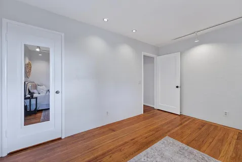 an empty room with wooden floor and a bathroom