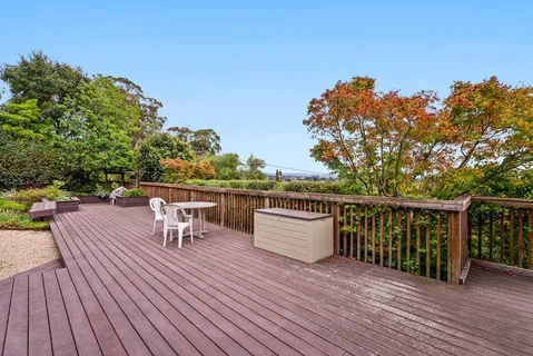 a view of a roof deck with table and chairs a barbeque with wooden floor and fence