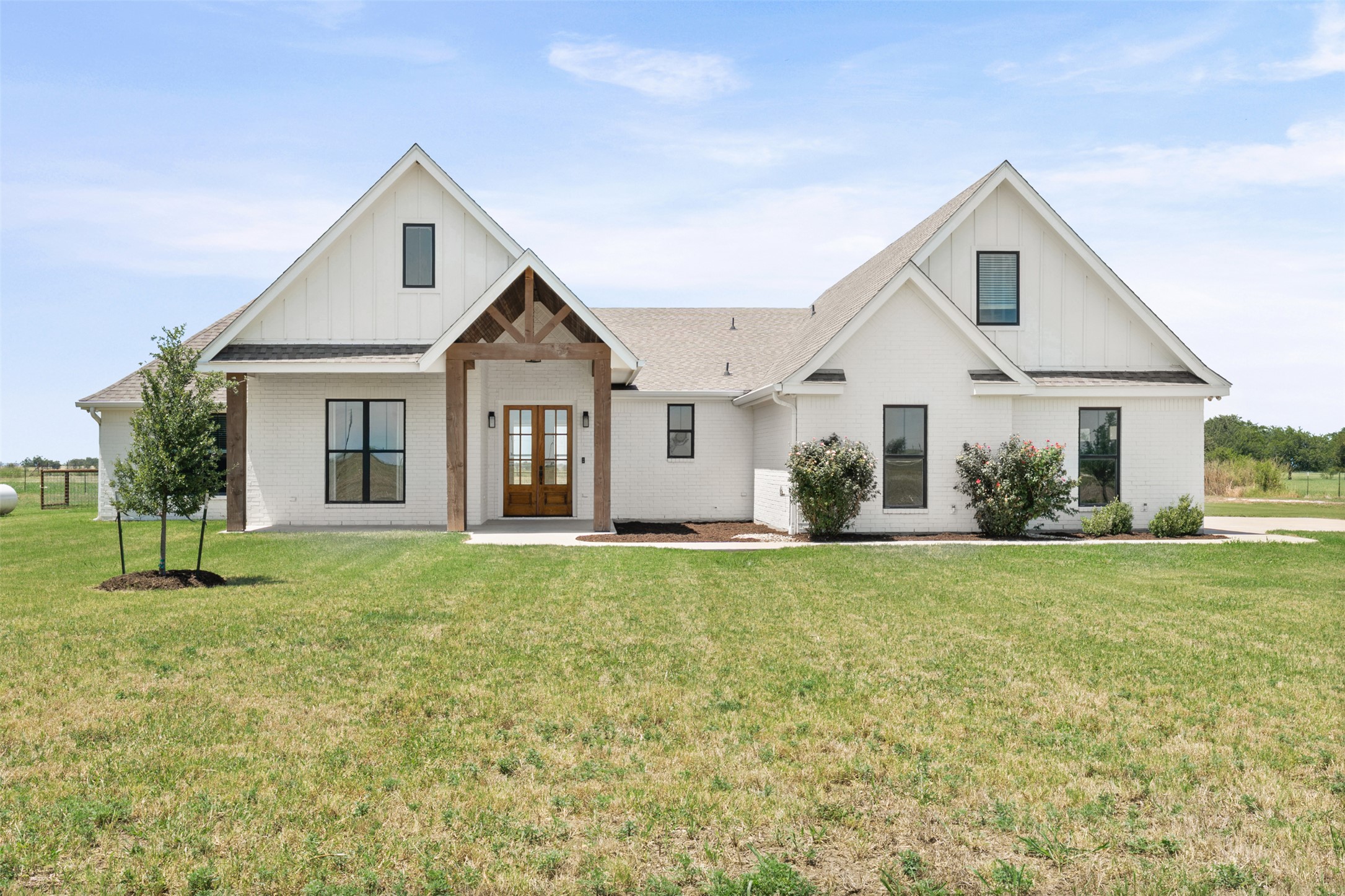 Crisp white brickwork and warm wooden gables create an inviting modern farmhouse exterior.