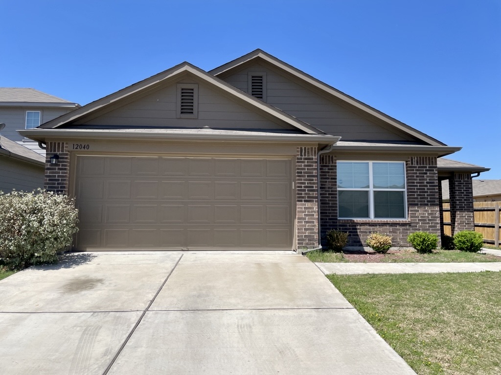 12040 Riparian Road Manor, TX 78653 - Photo 1 of 23 Classic brick and siding accents frame a neat concrete driveway and forward-facing garage.