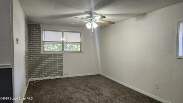 an empty room with windows and chandelier fan