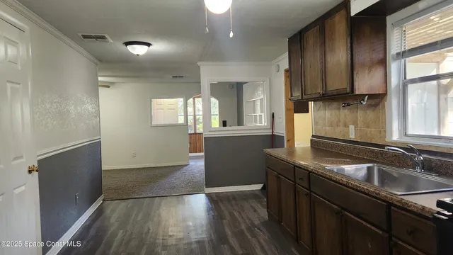 a kitchen that has a sink and a stove with wooden floor
